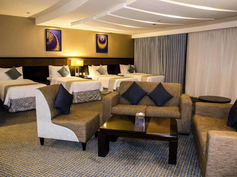 อัลคูฟราน ซาฟวะฮ์ โฮเต็ล มักกะฮ์ Hotel Mecca ภายนอก รูปภาพ The photo shows a spacious hotel room that features two large beds with decorative pillows. There is a sitting area with a modern sofa and a coffee table, complemented by two accent chairs. The room is elegantly decorated, with artwork on the walls a